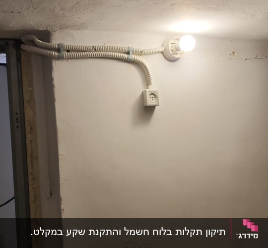 מנורה דולקת, שקע חשמל, צינור חשמל על קיר